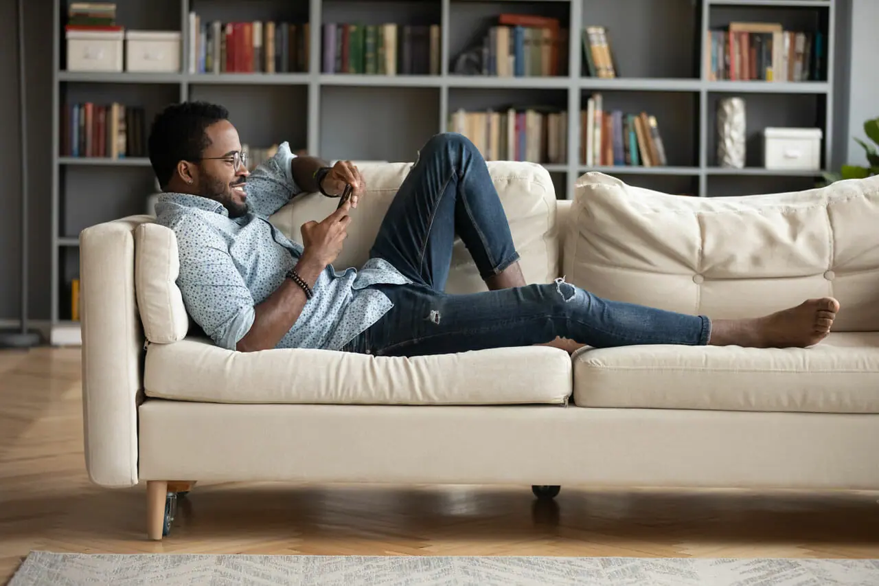 Homme détendu utilisant un téléphone sur un canapé.